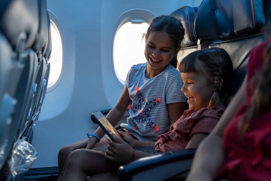 2 meisjes in een vliegtuig met een tablet